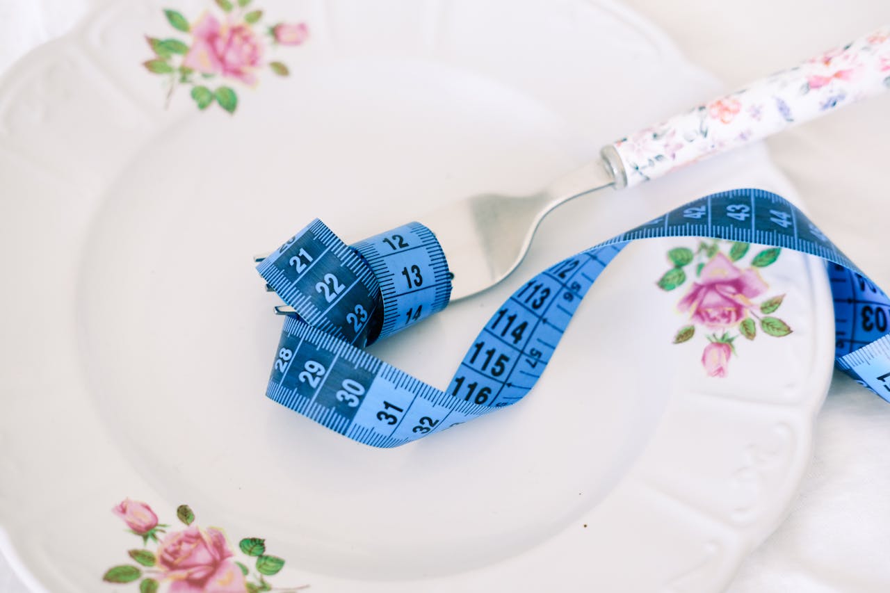 The Art of Drawing Readers In: Your attractive post title goes here A floral plate with a fork and blue measuring tape symbolizing dieting or healthy eating.